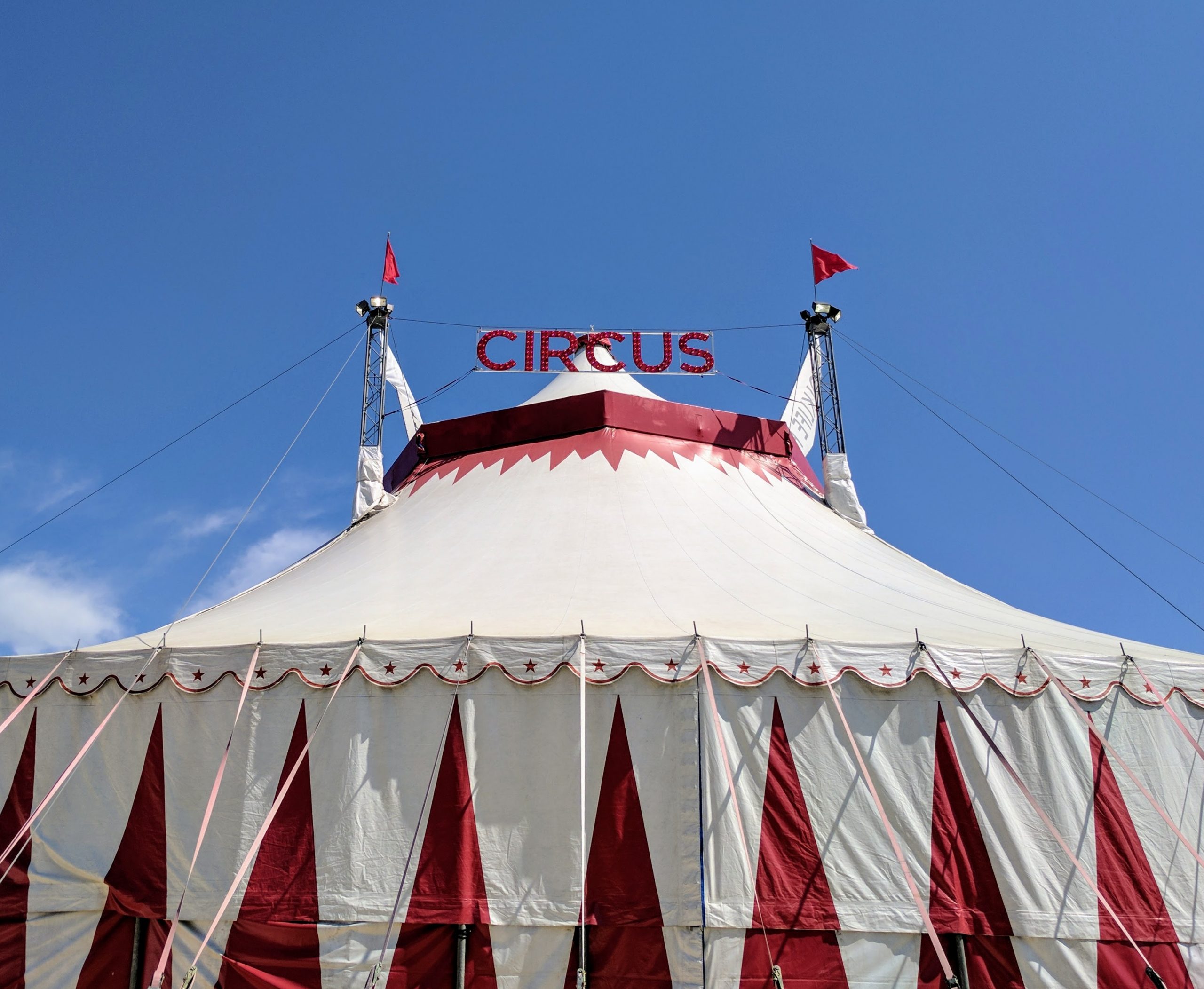 Photo of a circus tent against a blue sky.