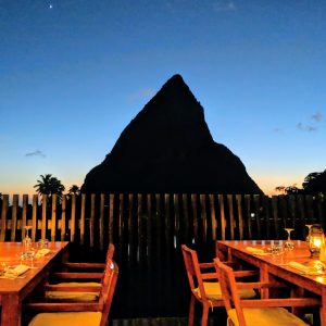 Photo of a mountain peak in shadow with restaurant tables set in front.
