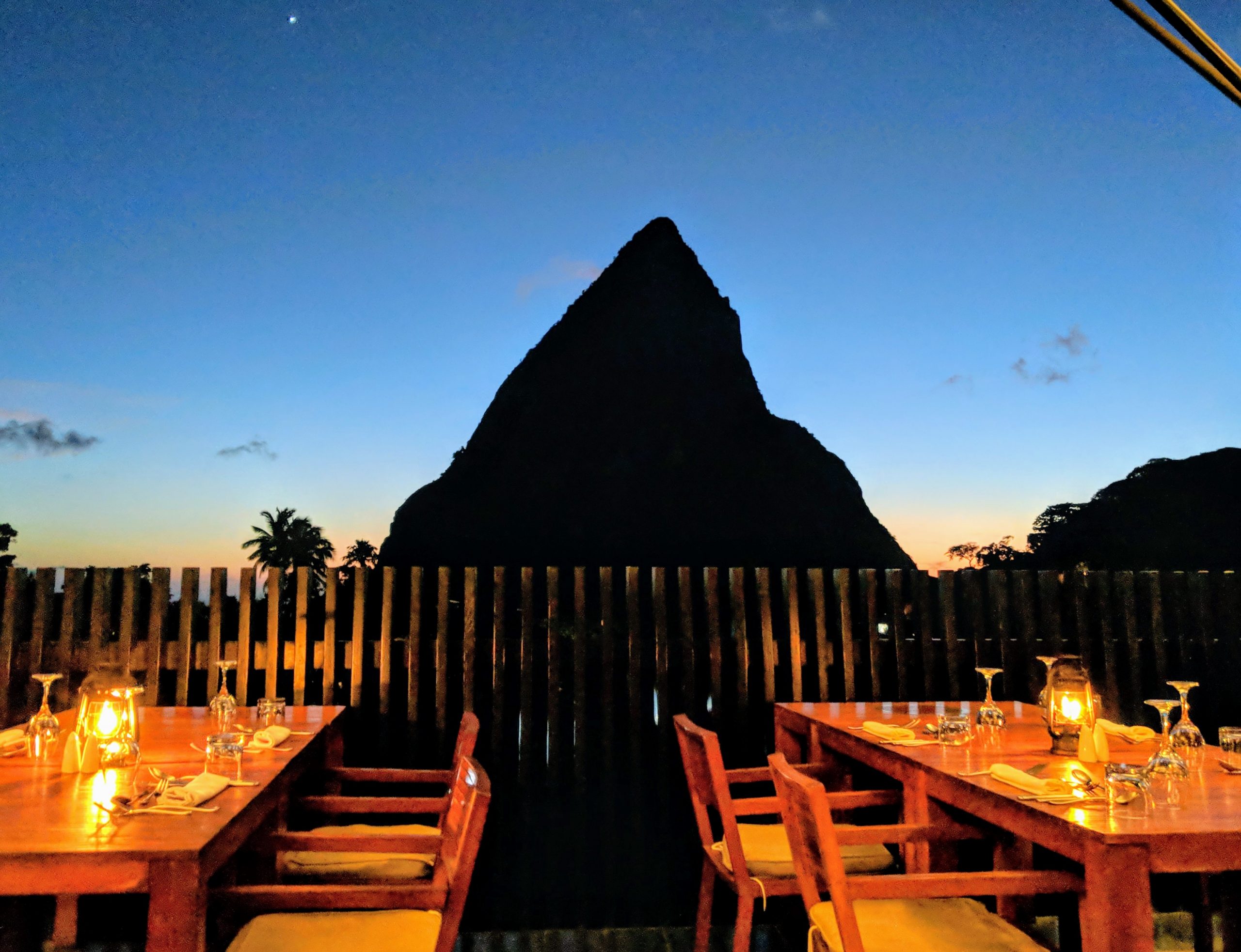 Photo of a mountain peak in shadow with restaurant tables set in front.