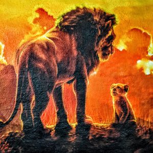 Photo of an exterior wall mural depicting an adult male lion and his cub.