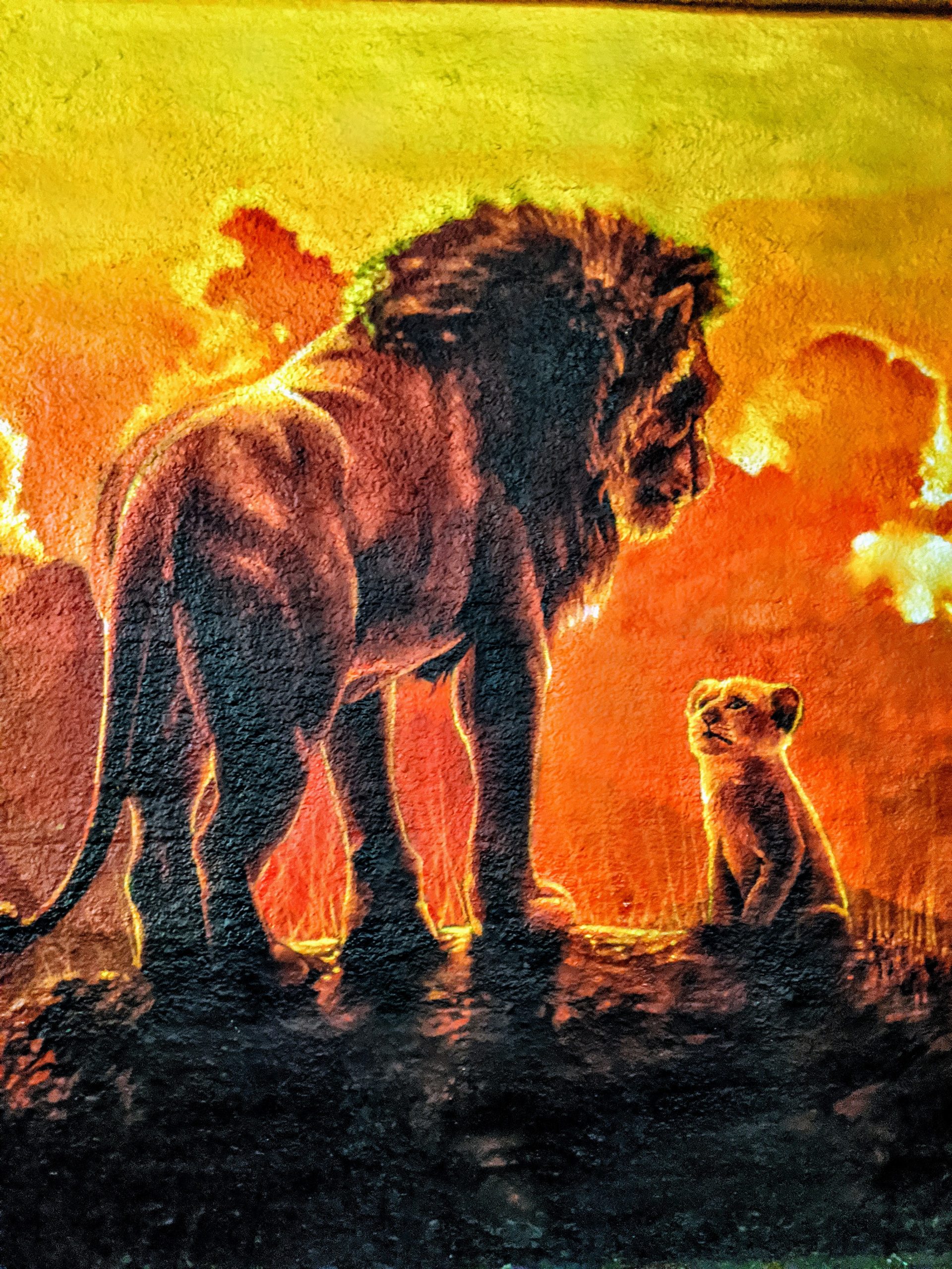 Photo of an exterior wall mural depicting an adult male lion and his cub.